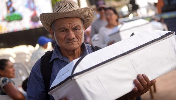 Un hombre lleva los restos recientemente exhumados de una de las víctimas de la masacre de El Mozote, durante su funeral por la conmemoración de los asesinatos de 1981 en El Salvador. (MARVIN RECINOS / AFP).