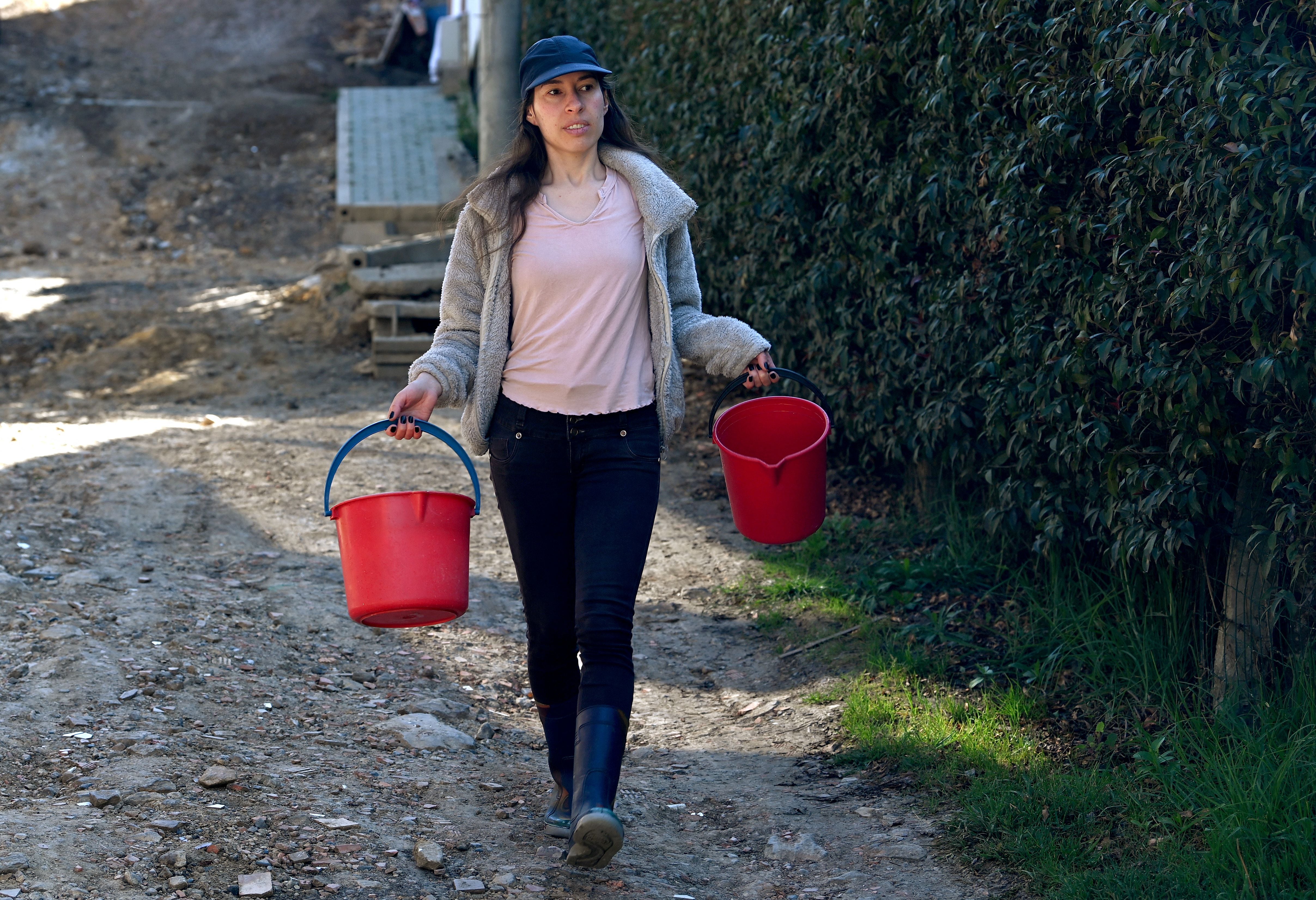 Graphic designer Clara Escobar carries buckets to collect drinking water from a tanker truck in La Calera, near Bogotá, on April 10, 2024. (Photo by Daniel MUÑOZ/AFP).