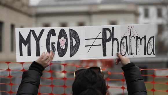 Fotografía de archivo del 13 de enero de 2020 de una mujer sosteniendo un letrero durante una protesta frente al Congreso de Nueva Jersey, en Trenton. El letrero lee "Mi Dios no es lo mismo que las farmacéuticas". (AP Foto/Seth Wenig, Archivo)