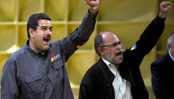 El entonces presidente interino de Venezuela, Nicolás Maduro (izq.), y el ministro de Cultura, Pedro Calzadilla, cantan durante la inauguración de la Feria del Libro en Caracas el 13 de marzo de 2013. (Foto de JUAN BARRETO / AFP).