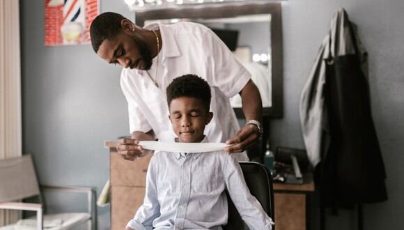 Un barbero preparando a un niño para su corte de cabello. | Imagen referencial: RODNAE Productions / Pexels