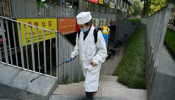 Una trabajadora desinfecta las escaleras de un restaurante de Beijing, China. (Foto: AFP/ Greg Baker)
