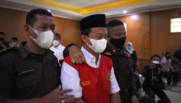 El profesor indonesio Herry Wirawan es escoltado antes de su juicio en un tribunal en Bandung, Java Occidental, el 15 de febrero de 2022. (TIMUR MATAHARI / AFP).