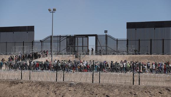 Migrantes esperan a orillas del Río Grande para ser procesados por la Patrulla Fronteriza Sector El Paso, Texas, después de cruzar desde Ciudad Juárez, México, el 10 de mayo de 2023. (Foto de HERIKA MARTINEZ / AFP)