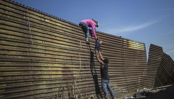 Un grupo de migrantes centroamericanos trepa la valla fronteriza entre México y Estados Unidos, cerca del paso fronterizo El Chaparral, en Tijuana, el 25 de noviembre de 2018. (Foto de Pedro PARDO / AFP).