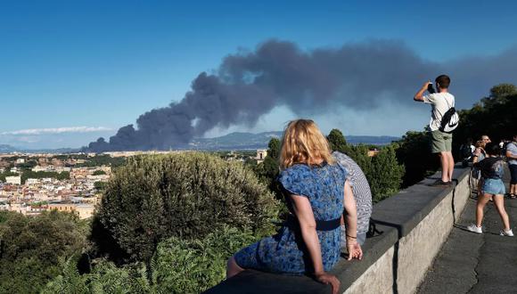 Gente en la Piazza Garibaldi, en la colina de Gianicolo, mira el humo que se eleva después de que estalló un incendio cerca del parque arqueológico del distrito de Centocelle, en el este de Roma.