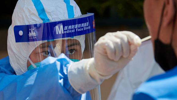 Un trabajador de la salud que usa equipo de protección personal realiza una prueba de hisopado para detectar el coronavirus covid-19 en Shanghai, China, el 17 de abril de 2022. (LIU JIN / AFP).