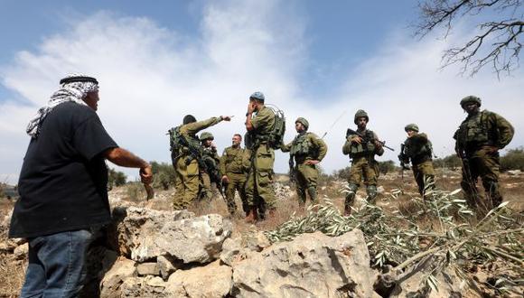 Granjeros palestinos discuten con soldados israelíes que les han cortado el paso de camino a un campo de olivos para realizar la cosecha. (Foto referencial: EFE)