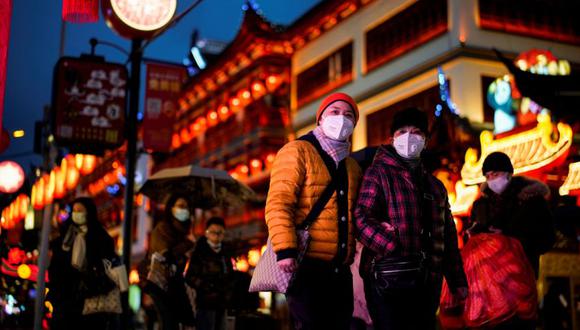Las personas que usan máscaras protectoras caminan por un área decorada con linternas antes de la festividad del Año Nuevo Lunar chino, luego de nuevos casos de enfermedad por coronavirus en Shanghái, China. (Foto: REUTERS/Aly Song).