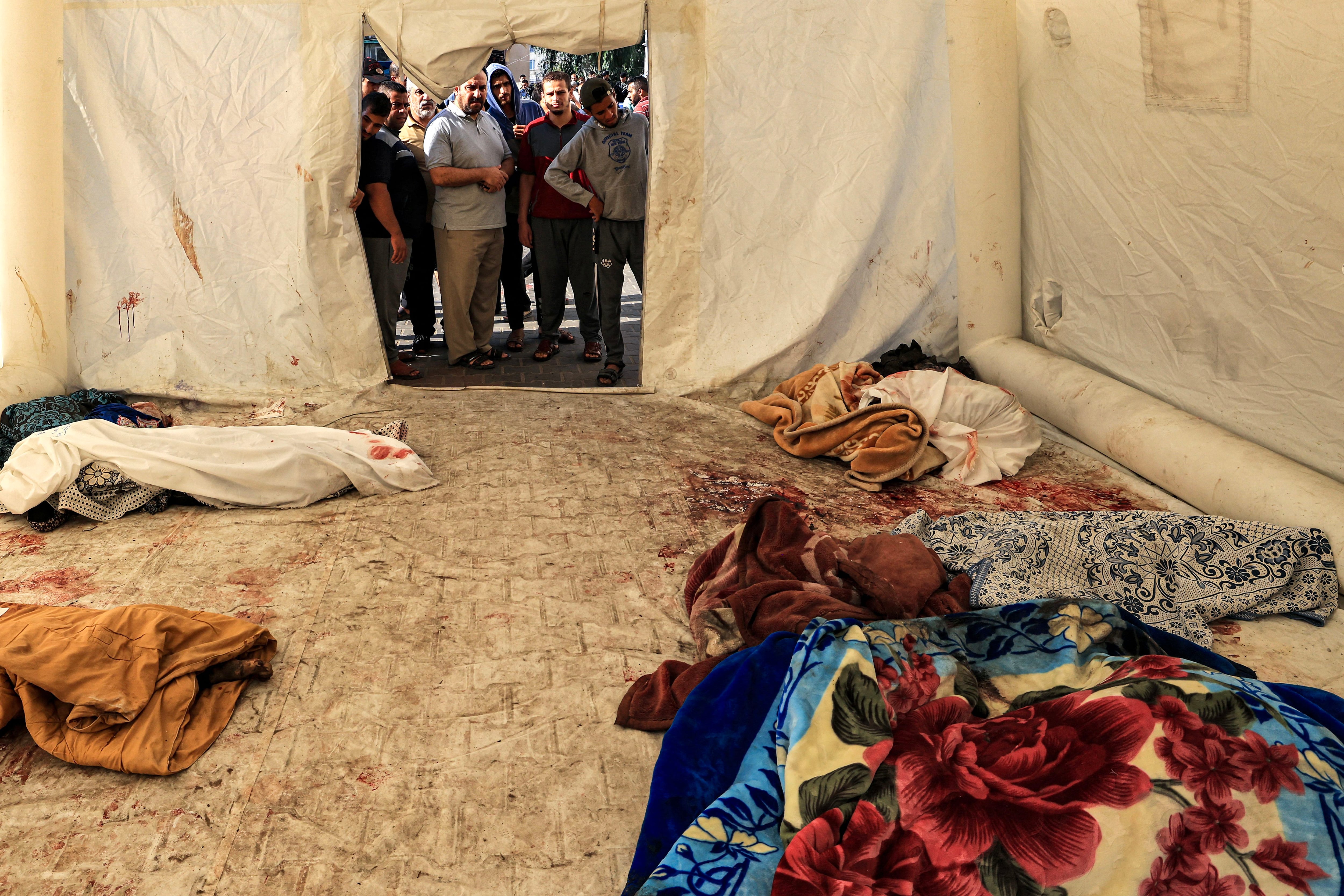 The bodies of the victims of the night attack on the Ahli Arab hospital are placed in a makeshift tent in central Gaza on October 18, 2023. (AFP photo).