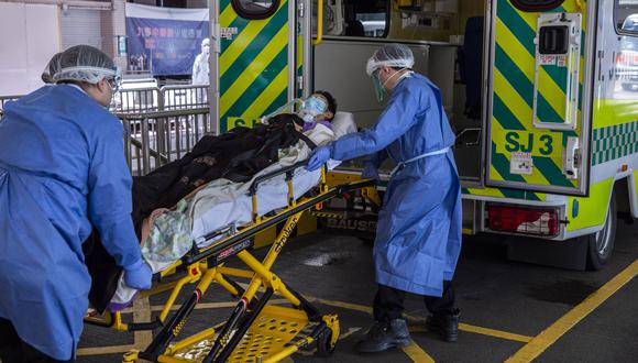 Una persona (C) es trasladada a una ambulancia fuera del Hospital Queen Elizabeth en Hong Kong el 10 de marzo de 2022, ya que el gobierno anunció que el hospital se utilizará solo para pacientes con Covid-19. (Foto de ISAAC LAWRENCE / AFP)