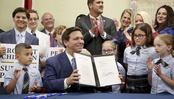El gobernador de Florida, Ron DeSantis, muestra los derechos de los padres en la educación firmados, también conocido como el proyecto de ley Don't Say Gay, flanqueado por estudiantes de primaria en la escuela Classical Preparatory en Shady Hills.