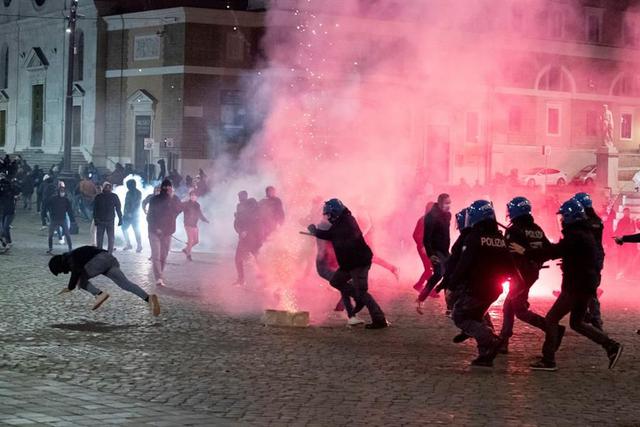 La policía antidisturbios y miembros del grupo de extrema derecha Forza Nuova se enfrentan durante una protesta contra las nuevas restricciones por coronavirus, en Piazza del Popolo, Roma. (EFE / EPA / CLAUDIO PERI).