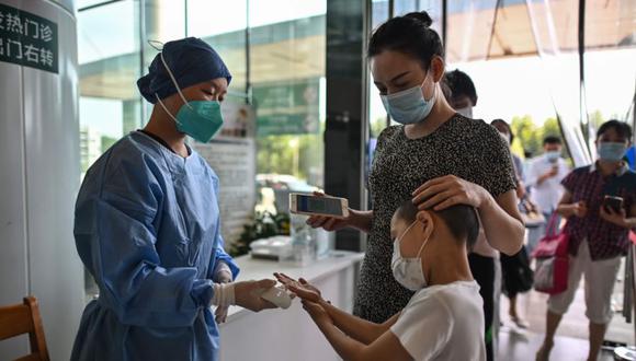 Un trabajador médico toma la temperatura de las personas que llegan al Hospital Tongji en Wuhan, provincia central de Hubei en China durante una visita de prensa a las instalaciones organizada por las autoridades locales. (Foto: AFP / Héctor RETAMAL).