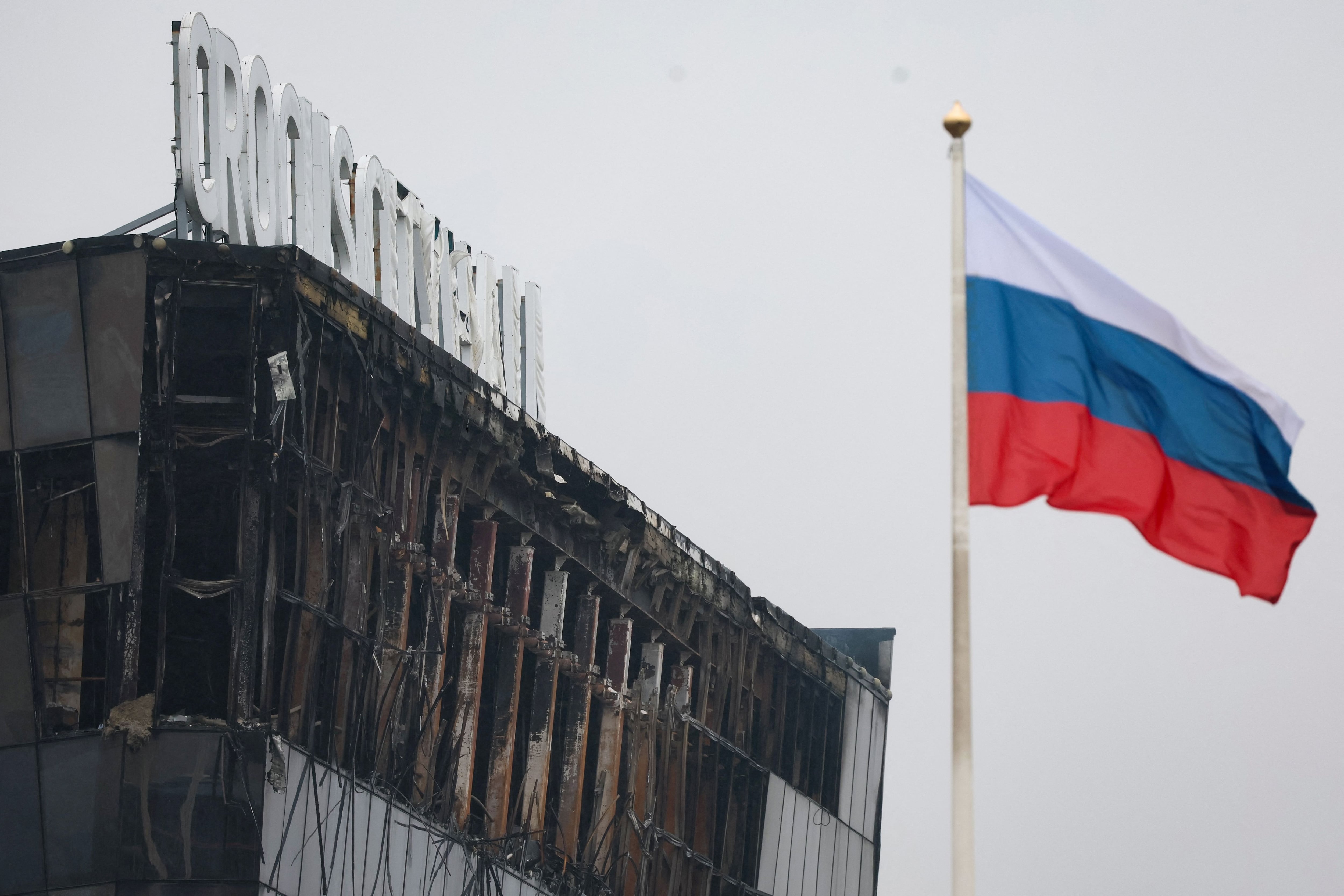 A Russian national tricolor flag flutters in the wind near the burned-out Crocus City Hall concert hall, the scene of the armed attack, in Krasnogorsk.  (Photo by STRINGER/AFP).