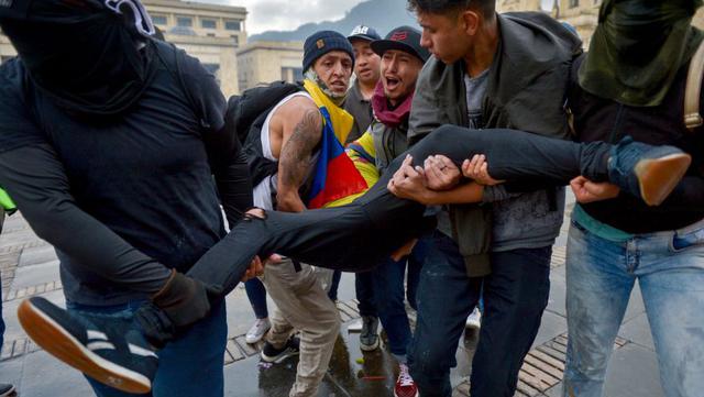 Un manifestante herido es llevado por sus compañeros durante los enfrentamientos después de una huelga nacional convocada por estudiantes, sindicatos y grupos indígenas para protestar contra el gobierno del presidente colombiano Ivan Duque. (Foto: AFP).