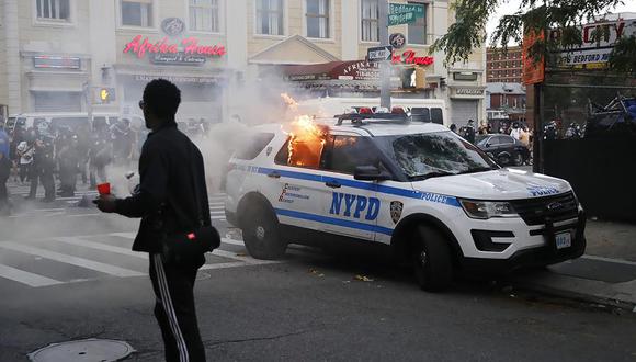 Los mkanifestantes incendian un carro  del Departamento de Policía de la ciudad de Nueva York durante las manifestaciones contra la brutalidad policial tras la muerte de George Floyd. (EFE / EPA / KEVIN HAGEN).