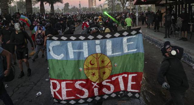 Un manifestante antigubernamental sostiene una bandera mapuche durante una manifestación contra la policía luego de que un oficial fuera acusado de presuntamente empujar a un joven desde un puente durante una protesta anterior en Santiago, Chile. (AP/ Esteban Felix).