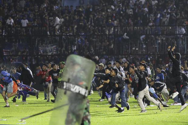 Fanáticos invaden la cancha durante un partido de fútbol en el estadio Kanjuruhan en Malang, en Java Oriental, Indonesia. (Foto AP/Yudha Prabowo).