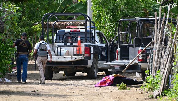 Las fuerzas de seguridad pasan junto a un cadáver en Coyuca de Benítez, estado de Guerrero, México, el 23 de octubre de 2023. (Foto de FRANCISCO ROBLES / AFP)
