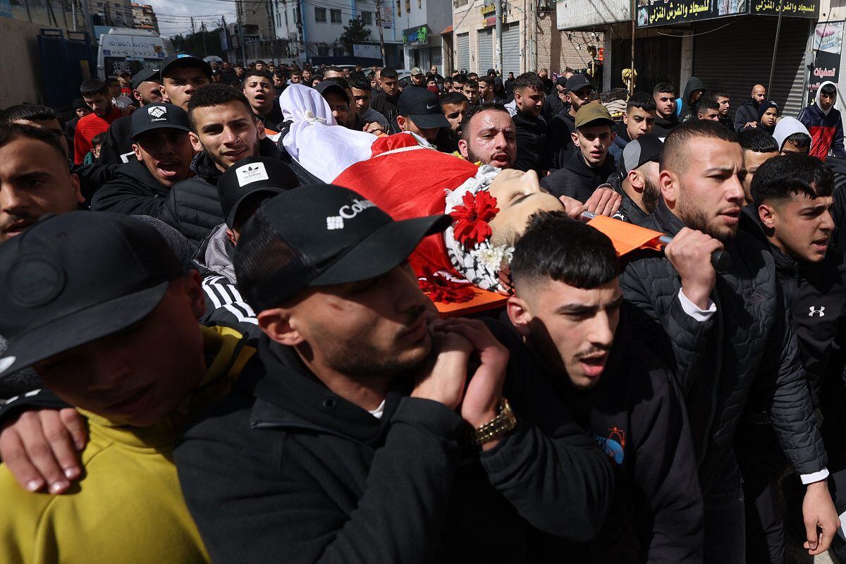 Palestinian people carry the body of 16-year-old Mustafa Abu Shalbak during his funeral in the Qalandiya refugee camp in the occupied West Bank on March 4, 2024. (Photo by Jaafar ASHTIYEH/AFP)