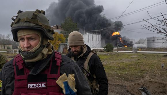 Un miembro del servicio de rescate de Ucrania y un soldado inspeccionan el lugar donde se eleva humo negro después de un ataque en Kherson, el 20 de noviembre de 2022. (BULENT KILIC / AFP).