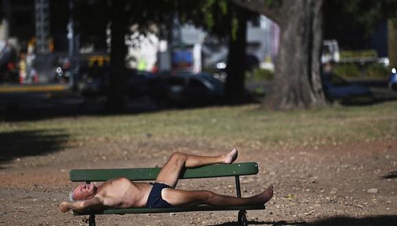 Un hombre toma el sol en un banco de un parque en los Bosques de Palermo en Buenos Aires, Argentina, en medio de una ola de calor la madrugada del viernes 14 de enero de 2022.  (AP Foto/Mario De Fina)