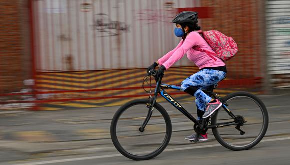 Una mujer usa una máscara facial como medida preventiva contra la propagación del nuevo coronavirus, COVID-19, monta una bicicleta en Cali, Colombia. (AFP / Luis ROBAYO).