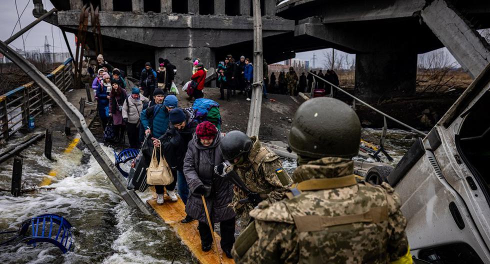 Los evacuados cruzan un puente destruido por Rusia mientras huyen de la ciudad de Irpin, al noroeste de Kiev, capital de Ucrania, el 7 de marzo de 2022. (DIMITAR DILKOFF / AFP).