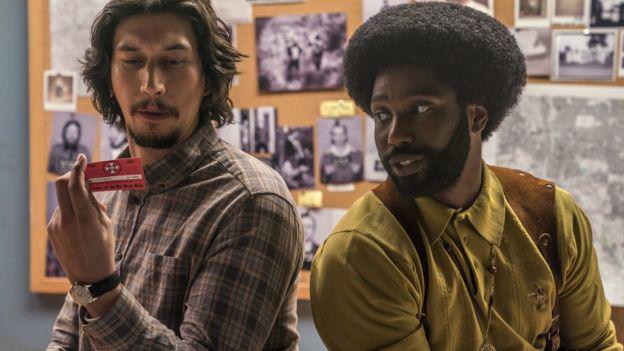 El actor Adam Driver (izquierda) interpreta el papel de "Chuck", el policía blanco que iba a las reuniones del KKK haciéndose pasar por Stallworth.