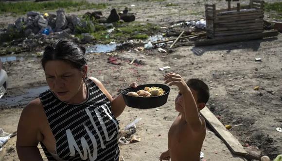 Andrea Calisti sostiene un molde de pan dulce donado mientras su hijo Nathanael de 7 años toma un pedazo, entregado por miembros de la organización social Movimiento de Trabajadores Excluidos en el barrio de Buenos Aires, Argentina.