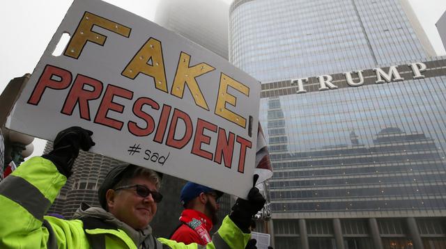Protestantes frente a la torre Trump, en Nueva York. "Falso presidente", dice el carte que lleva una de ellas. (AFP)