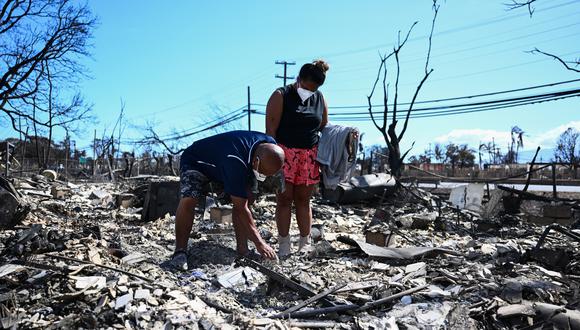 Davilynn Severson y Hano Ganer buscan sus pertenencias entre las cenizas de la casa de su familia después de un incendio forestal en Lahaina, en el oeste de Maui, el 11 de agosto de 2023. (Foto de Patrick T. Fallon / AFP).