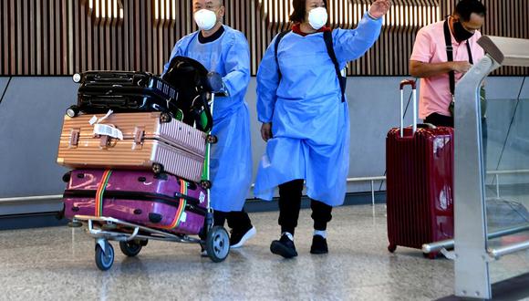 Los viajeros internacionales que usan equipo de protección personal (PPE) llegan al aeropuerto Tullamarine de Melbourne el 29 de noviembre de 2021, cuando Australia registra sus primeros casos de la variante ómicron del coronavirus. (William WEST / AFP).