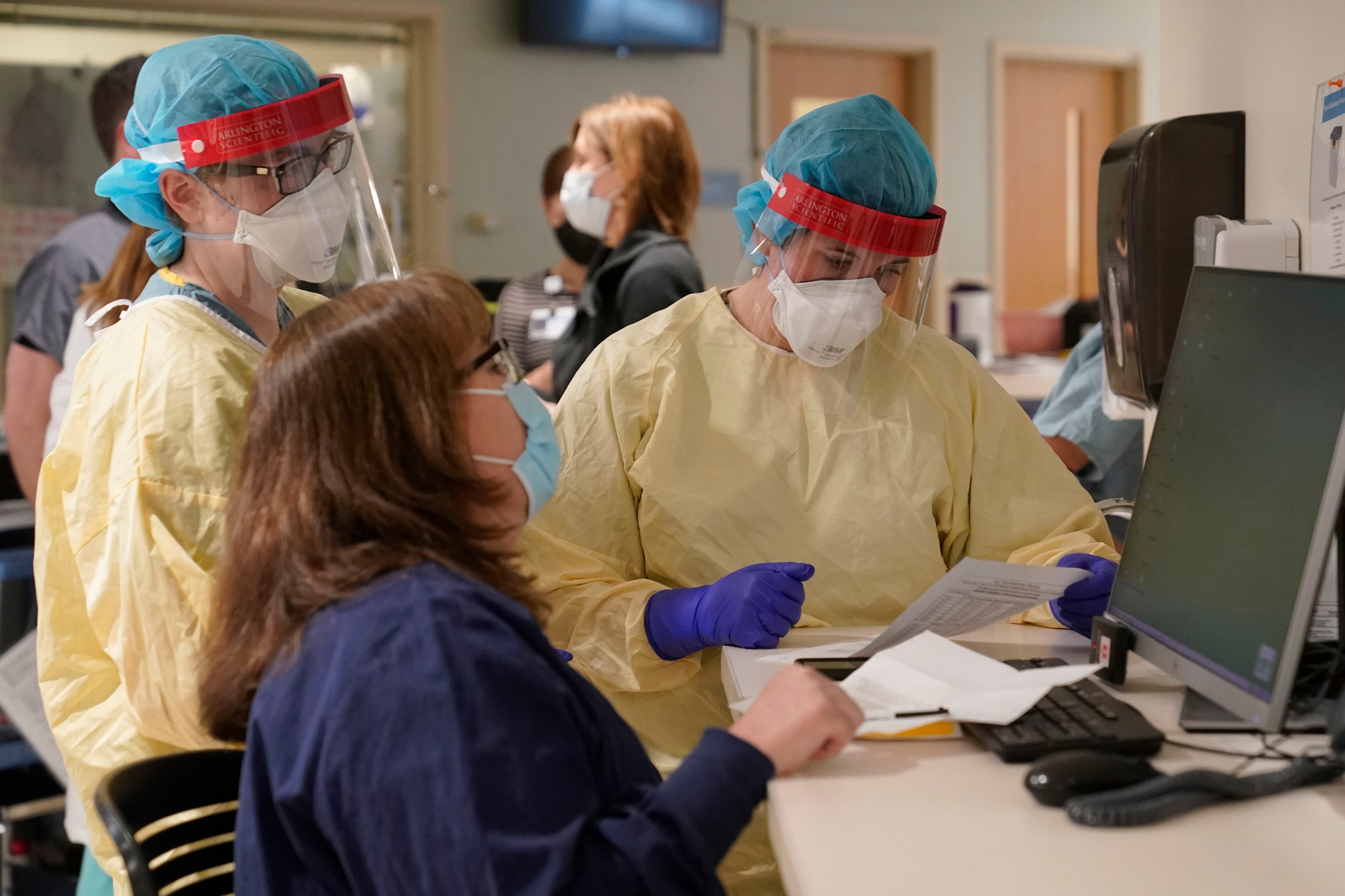 Registered nurses Sarah Carr, top left, and Lindsay Holloran, right, are outfitted in protective gear before entering a patient's room in the COVID-19 Intensive Care Unit at Dartmouth-Hitchcock Medical Center , in Lebanon.  (Photo: AP / Steven Senne)