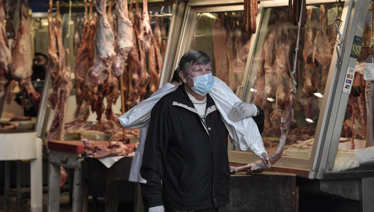 Coronavirus. Un hombre carga un trozo envuelto de cordero mientras camina por el principal mercado de carne de Atenas, Grecia. Foto: AFP.