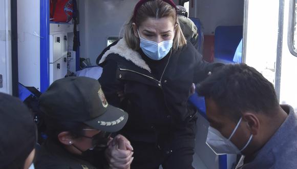 La expresidenta interina de Bolivia Jeanine Áñez  es asistida por una policía para bajar de una ambulancia que la llevó de vuelta a la cárcel en que está recluida. (Foto: EFE/Stringer)