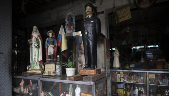 Una imagen del doctor venezolano José Gregorio Hernández (derecha), sobre un expositor junto a otras estatuas de santos, en una tienda esotérica en Caracas, Venezuela, el 28 de abril de 2021. Conocido como el "médico de los pobres", Hernández será beatificado el 30 de abril por la Iglesia católica, un paso hacia su santidad. (AP Foto/Ariana Cubillos)