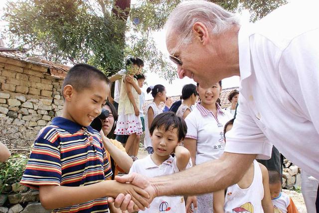 El entonces presidente del Comité de Relaciones Exteriores del Senado de los Estados Unidos, Joe Biden (derecha), saluda a Gao Shan, de nueve años, en el pueblo de Yanzikou, al norte de Beijing (China). Imagen del 10 de agosto de 2001.  (AFP / POOL / GREG BAKER).