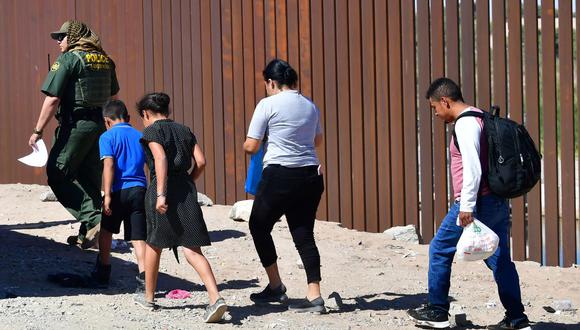 Los migrantes siguen a un agente de la Patrulla Fronteriza de Estados Unidos al llegar al muro fronterizo con México en Yuma, Arizona, el 16 de mayo de 2022. (Frédéric J. BROWN / AFP).