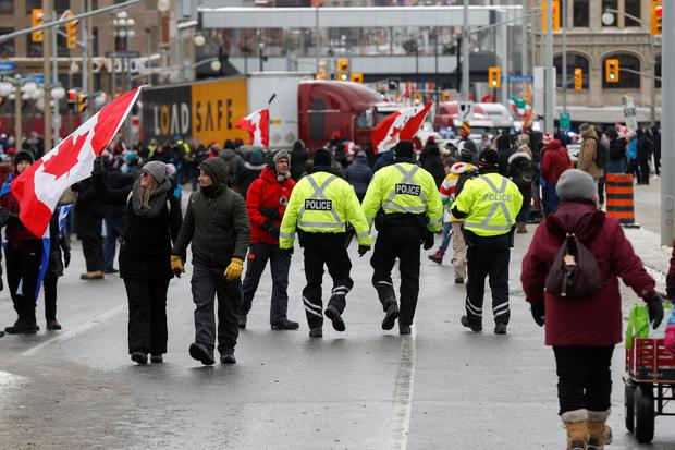 Police officers walk through the crowd, as truckers and supporters continue to protest coronavirus disease (COVID-19) vaccination mandates, in Ottawa, Ontario, Canada.  (Photo. REUTERS/Lars Hagberg). 
