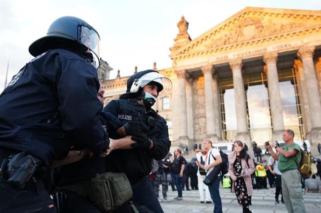 La policía detiene a un manifestante frente al edificio del Reichstag después de que los protestantes intentaran subir las escaleras. Ocurrió en medio de una manifestación en Berlín en contra de las medidas dictadas para frenar la pandemia de coronavirus en Alemania. (EFE / EPA / CLEMENS BILAN).