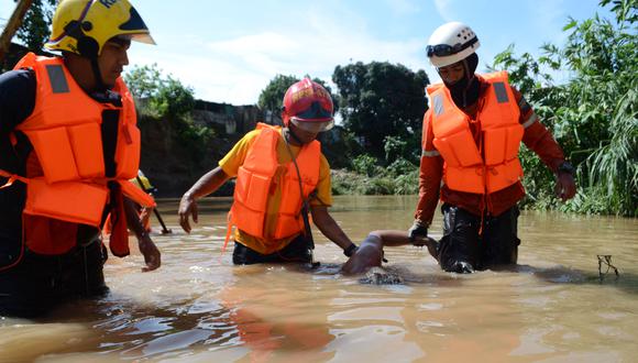 Miembros de Protección Civil sostienen a un hombre fallecido tras una inundación en Barquisimeto, estado Lara, Venezuela.