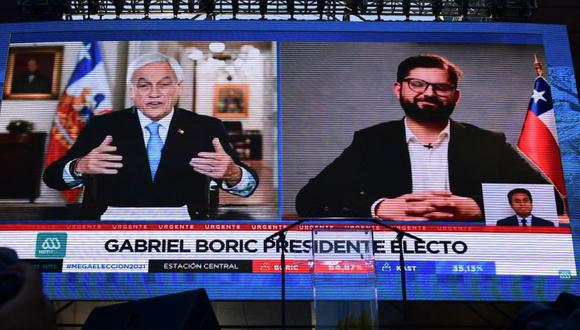 Vista de una pantalla gigante que muestra al presidente chileno Sebastián Piñera (izq.) felicitando al candidato presidencial chileno Gabriel Boric, del partido Apruebo Dignidad en Santiago. (Foto: MARTIN BERNETTI / AFP).