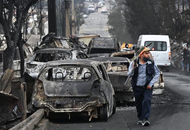 Un hombre pasa junto a vehículos quemados después de un incendio forestal en Quilpue, Viña del Mar, Chile, el 4 de febrero de 2024. (Foto de RODRIGO ARANGUA/AFP).