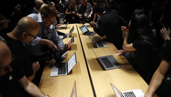 Miembros de los medios de comunicación se reúnen alrededor de una mesa que muestra la computadora portátil Apple MacBook Pro en 2016. (Foto: AFP)