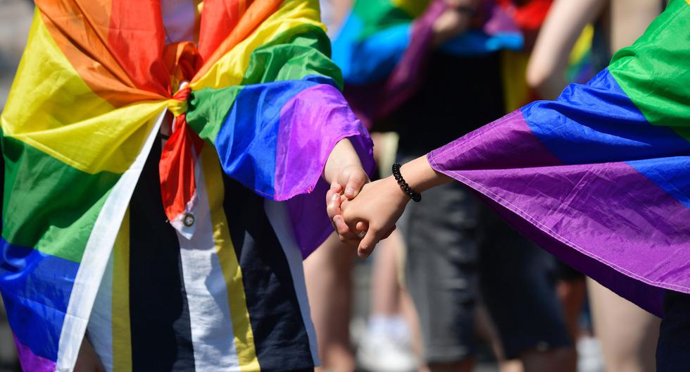Dos personas que llevan banderas del arco iris se toman de las manos mientras participan en una Marcha del Orgullo en Berlín el 27 de junio de 2020. (Foto de Tobias SCHWARZ / AFP).