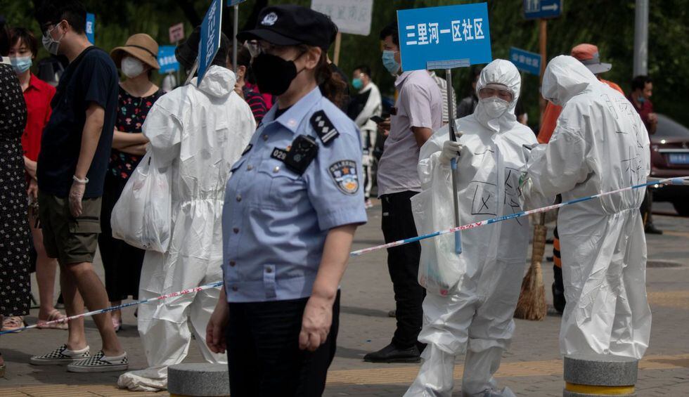 El personal médico, que usa un equipo de protección completo contra el coronavirus, lleva carteles para ayudar a las personas que viven cerca o han visitado el mercado Xinfadi en Beijing. (AFP / NOEL CELIS). 