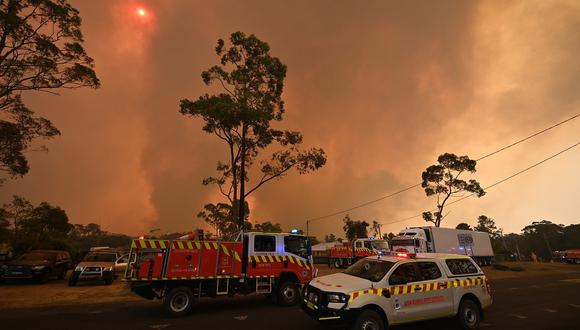 Los camiones de bomberos se ven estacionados en una carretera mientras arde un incendio forestal en Bargo, al suroeste de Sydney. (AFP)