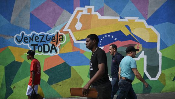 La gente camina junto a un mural que hace campaña a favor de un referéndum para pedir a los venezolanos que consideren la anexión de la región de Esequibo administrada por Guyana, en el barrio 23 de Enero de Caracas el 28 de noviembre de 2023. (Foto de Federico PARRA/AFP)